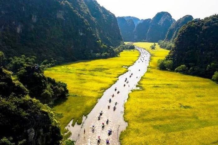 Boats on the river between green fields and limestone mountains in Ninh Binh